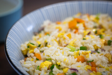close up of a bowl of fried rice with vegetables and eggs.
