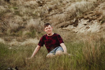 Fototapeta premium Adolescent boy sitting in grass in the Australian bush