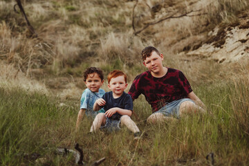 Three brothers sitting together on a rock in the Australian bush