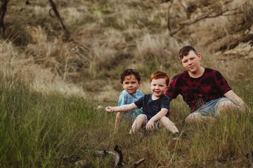 Three brothers sitting together on a rock in the Australian bush