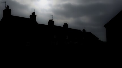 Obraz premium Silhouetted houses under a dark, cloudy sky.
