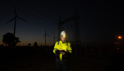 Engineer man working with tablet at windmill farm Generating electricity clean energy. Wind turbine farm generator by alternative green energy.