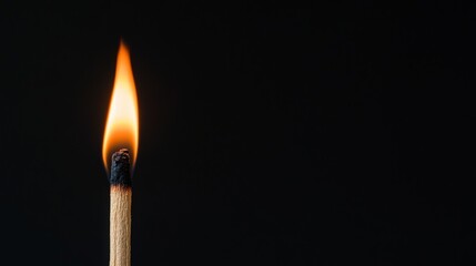 Lit matchstick on black background with copy space.