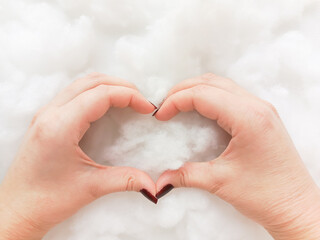 A woman holds her hands in the shape of a heart against the background of a silkworm filler. The...