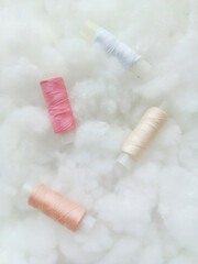 Coils with pink, beige and white threads on airy soft clouds, sintepon, cotton wool. Sewing production, atelier.