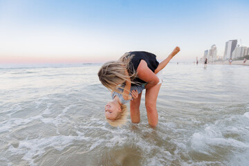 Mother lowering son into water on the beach at the Gold Coast