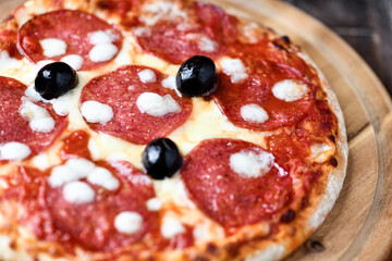 Pizza with salami and mozzarella cheese. Wooden background. Soft focus. Close up.	