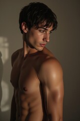 Fototapeta premium Shirtless male model with a lean, athletic build and chiseled features posing in warm studio lighting. Perfect for lifestyle, fashion, or fitness concepts in premium stock photography.