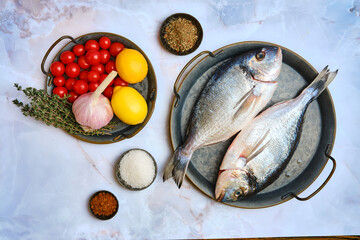 Fresh fish preparation with vegetables and herbs on a marble countertop for a flavorful meal