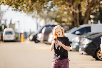 Pre-teen boy using mobile phone in car park