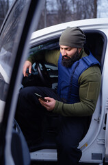 Bearded man wearing body armor sitting in car