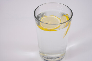 A refreshing glass of water with floating lemon slices on a white background. 