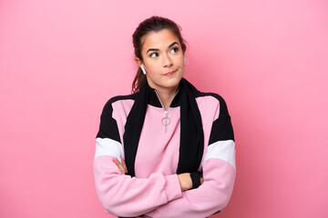 Young sport Brazilian woman isolated on pink background making doubts gesture while lifting the...