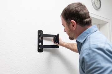 a man is assembling a TV bracket. He keeps instructions and is focused on the process. There are...