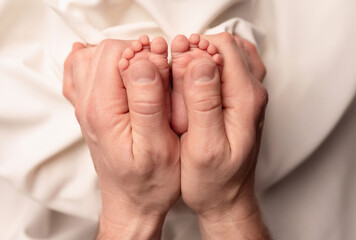 Baby feet of a newborn in dad's hands. On a white background.	