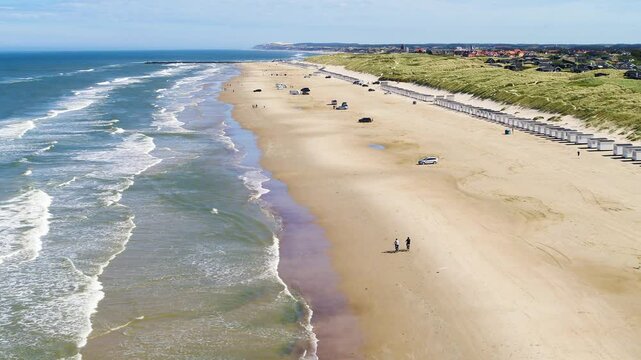Drone flying forwards over people biking on a beach