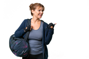 Middle-aged sport woman with sport bag over isolated background pointing to the side to present a product