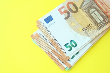 Big amount of one hundred and fifty euro money bills on yellow background