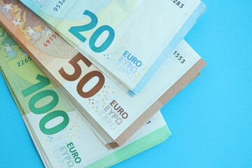 Big amount of one hundred, twenty and fifty euro money bills on blue background