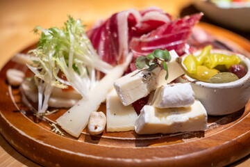 Cold cuts platter, variety of sliced meat and cheese with olives and nuts