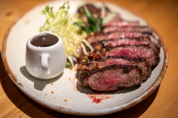 Medium rare wagyu meat served on plate with sauce and vegetable
