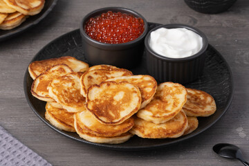 Delicious stack of golden pancakes served with cream and caviar on a rustic table