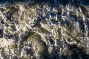 Rough flow of foaming water in the river, close-up, background