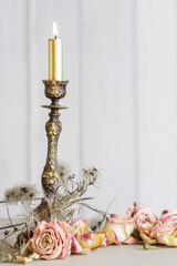 Decoration with an antique candlestick and dry roses.