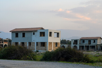 Deserted buildings stand quietly under a soft sunset sky in a forgotten development