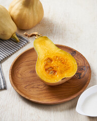 delicious sliced honey pumpkin with coconut cream sauce on a wooden plate in a white wooden background.