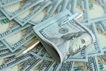 Golden pen clipping big amount of hundred dollar bills US banknotes