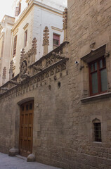 Gothic Quarter in Barcelona; stone wall with windows and roof with sculptures