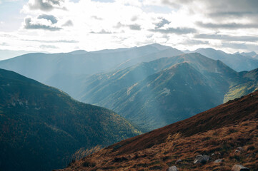Sunlit Mountain Range with Clouds and Valleys