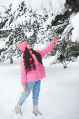 Pretty teenage girl 14-15 year old wearing pink warm jacket over snow outdoors. Winter time.