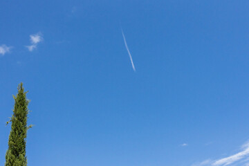 A blurry high-flying passenger plane and white streaks in the blue sky.