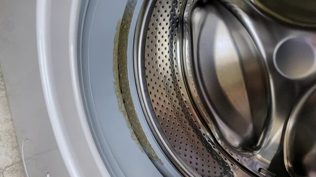 Dirty moldy rubber seal of the washing machine. Washing machine maintenance.