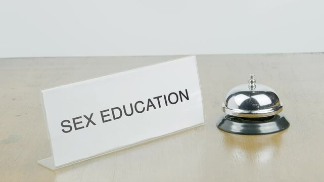 Sex Education Office or Room with Hand Ringing The Bell on Desk or Table Multiple Times
