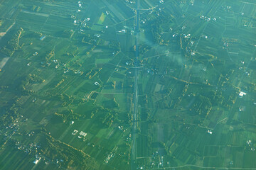 Captivating aerial view of a rural landscape with a central straight road dividing agricultural fields into geometric shapes, offering a striking look at land use patterns and rural planning