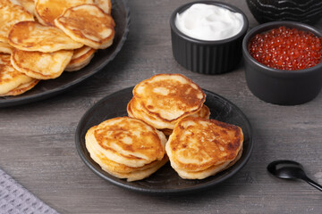 Delicious stack of golden pancakes served with cream and caviar on a rustic table