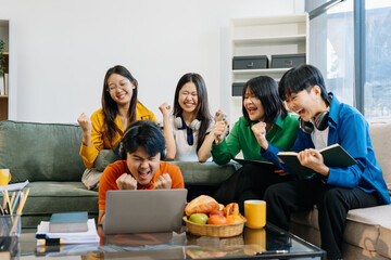 Happy group of college students use laptop feel excited overjoyed triumph with good news over smartphone or Tablet.