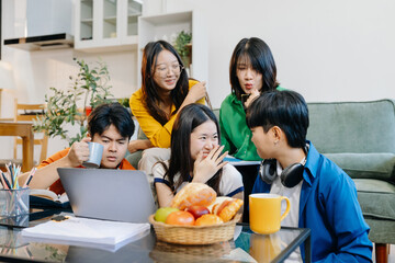 Asian college student reading a book study on laptop prepare for the exam or work on a group project at home.