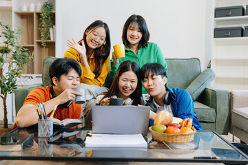 Asian college student reading a book study on laptop prepare for the exam or work on a group project at home.