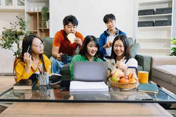 Asian college student reading a book study on laptop prepare for the exam or work on a group project at home.