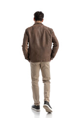Naklejka premium back view of relaxed fashion man stepping while holding pockets
