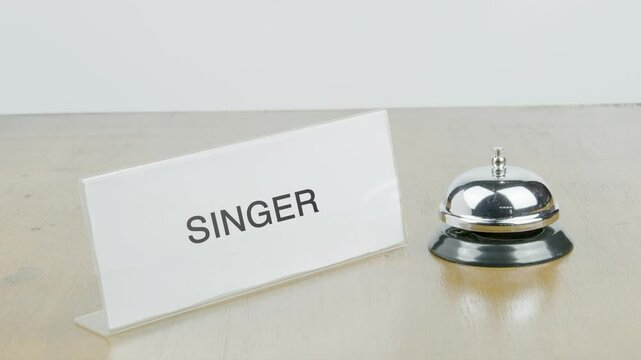 Singer Office or Room with Hand Ringing The Bell on Desk or Table Multiple Times