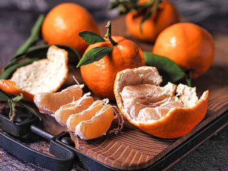A wooden cutting board with a few oranges on it