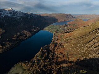 Dramatic aerial drone landscape in Autumn Winter of snowcapped mountains around Buttermere in Lake District at sunrise