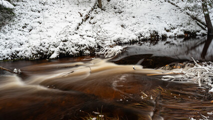 close-up view of a wild wild river, long exposure, blurred water, frozen ice formations in the river stream