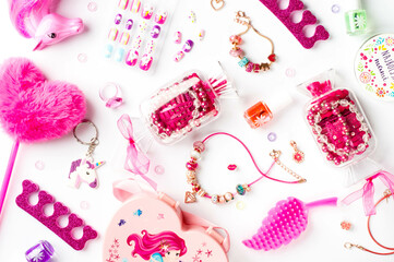 Pink accessories. Heart-shaped fluffy pen, colored false nails, candy-shaped containers with pink beads, nail polish bottles, a separator for pedicures, and jewelry items for girls.
