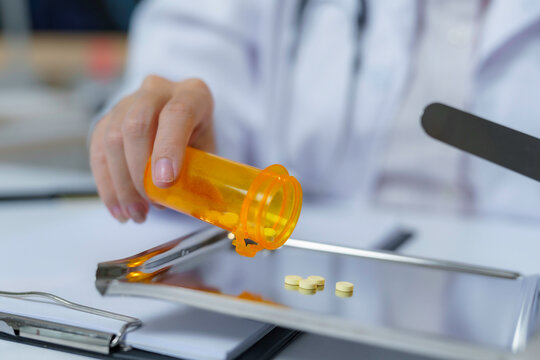 Close up of pharmacist pouring pills from prescription bottle onto counting tray, preparing medication for patient